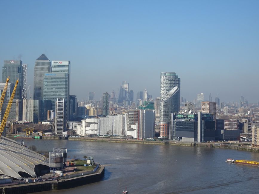 Aerial view of a modern urban cityscape featuring numerous high-rise office buildings and residential towers, with some structures made of glass and steel reflecting light, set against a background of